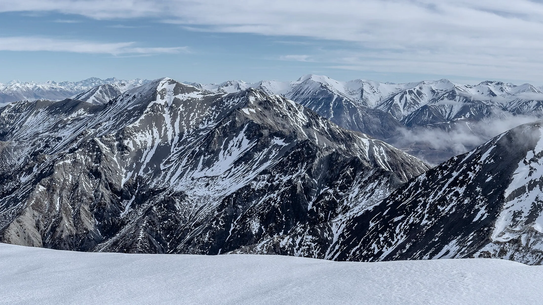 A high-altitude snow mountain range under quiet dawn light